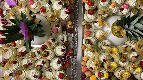 Festive dessert buffet with sweet treats in preserving jars, decorated with pineapples and orchids.