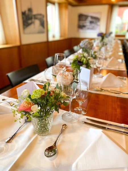 Elegant table setting in a traditional Swiss Sääli with wood-paneled walls and historic photographs.