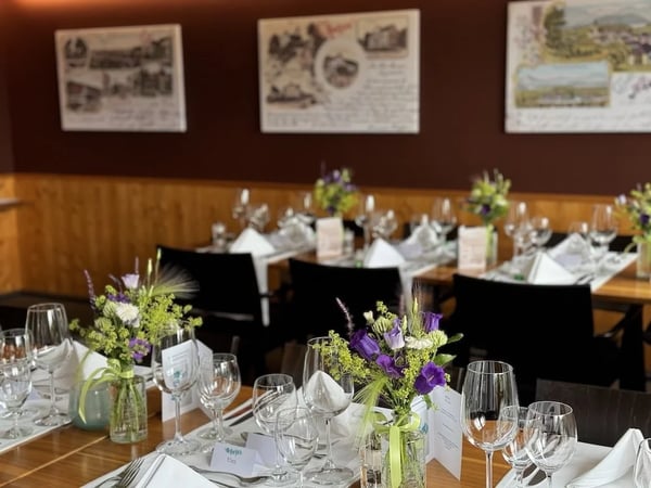 Close-up of table decoration with delicate flower arrangements in vintage glass vases, white tablecloth and elegant cutlery in the stuebli