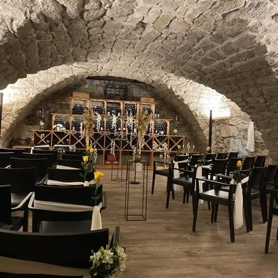 Gewölbekeller für Trauung eingerichtet mit Stuhlreihen und gelben Rosen als Dekoration. Weinlager als charakteristische Kulisse.