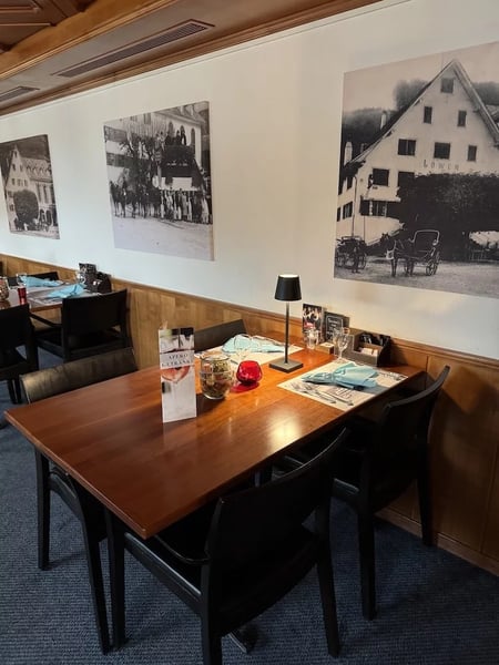 Modern restaurant interior ('Sääli') with historic black and white photographs adorning the white walls above wooden wainscoting. 