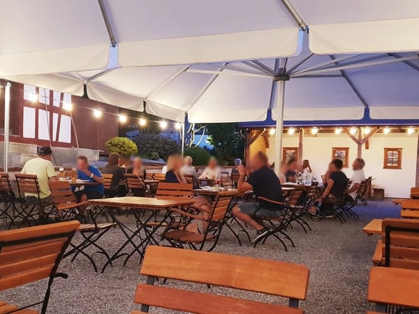 Cozy beer garden in the evening with atmospheric lighting under white umbrellas
