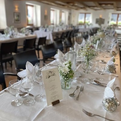 Hochzeitsgedeck mit Menükarte und weißer Blumendekoration. Lange Festtafel mit weisser Tischdecke