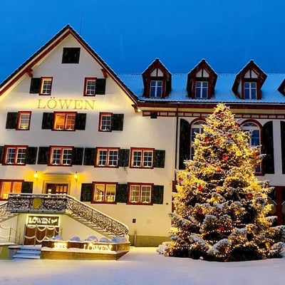 Löwen in winter with festively decorated Christmas tree. Illuminated facade at dawn.