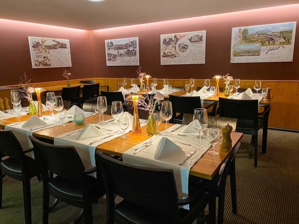 Formally set table in historic room with wood paneling and coffered ceiling. Hydrangeas and summer flowers in crystal vases in the Stuebli