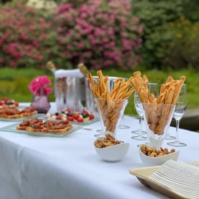 Aperitif buffet at Seleger Moor with bruschetta and crispy breadsticks. Blooming rhododendrons create picturesque backdrop.