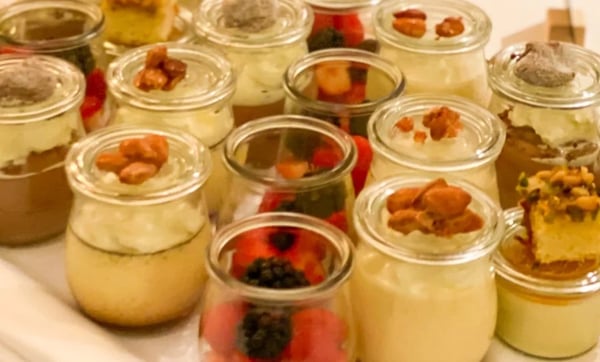 Fine desserts in small glasses, decorated with caramelized nuts and fresh berries.