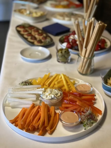 Colorful vegetable crudités - carrots, kohlrabi, and bell peppers - served with herb dip and cocktail sauce.