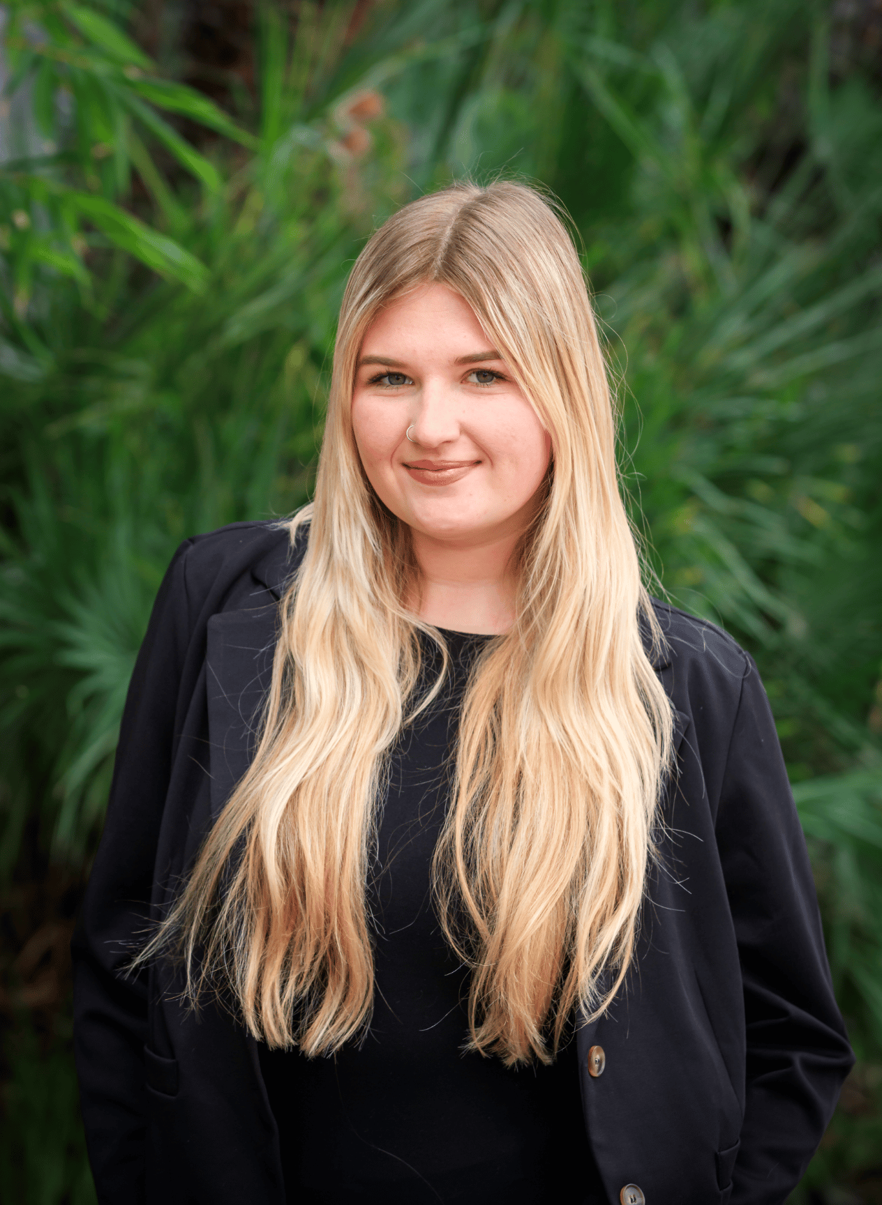 Young woman smiling at reception desk with Grand logo wall.