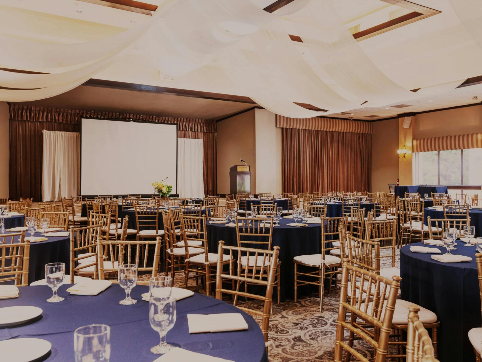 Grand Ballroom with rounds, stage, and warm chandelier glow.