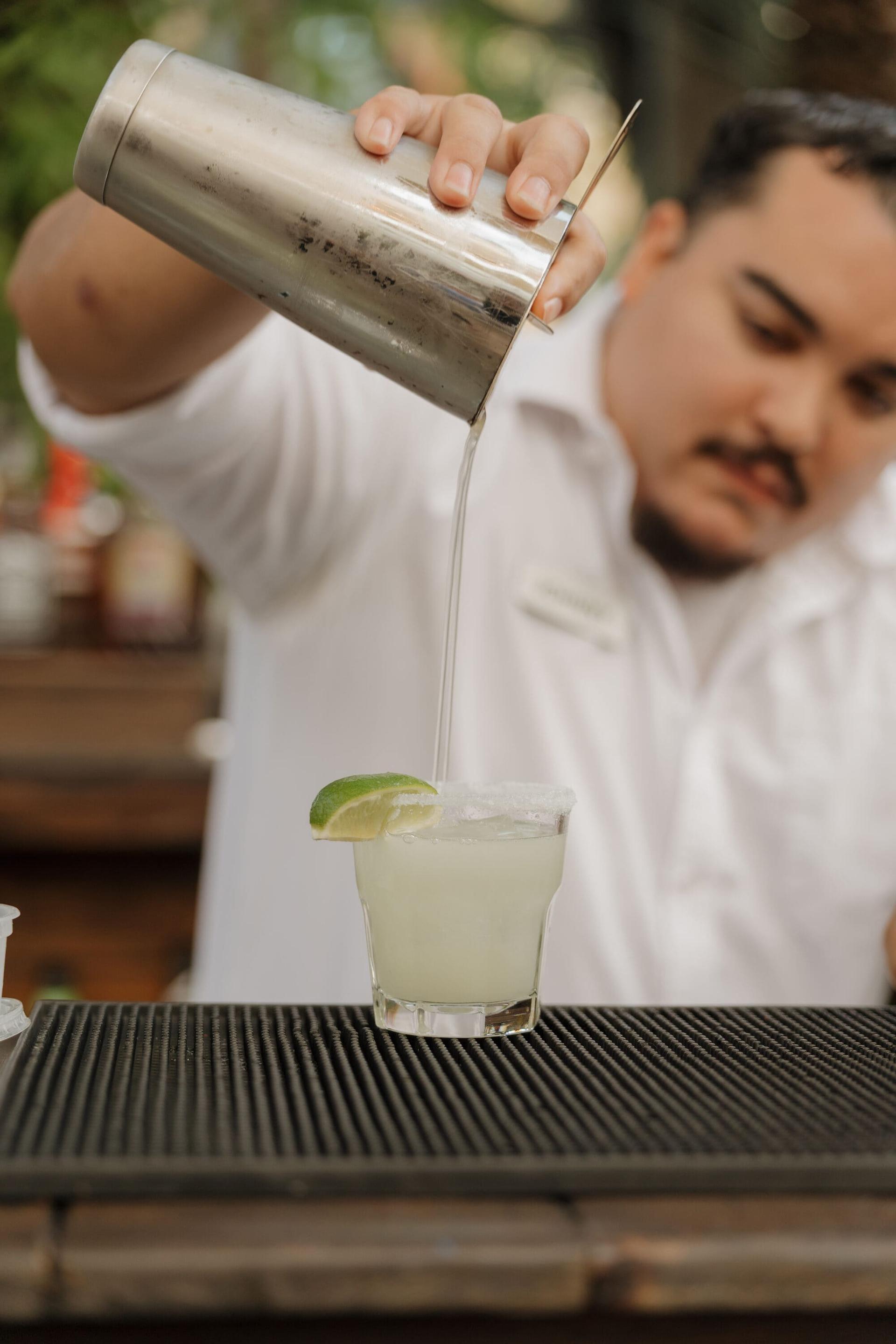 Bartender pouring a fresh margarita at the outdoor bar.