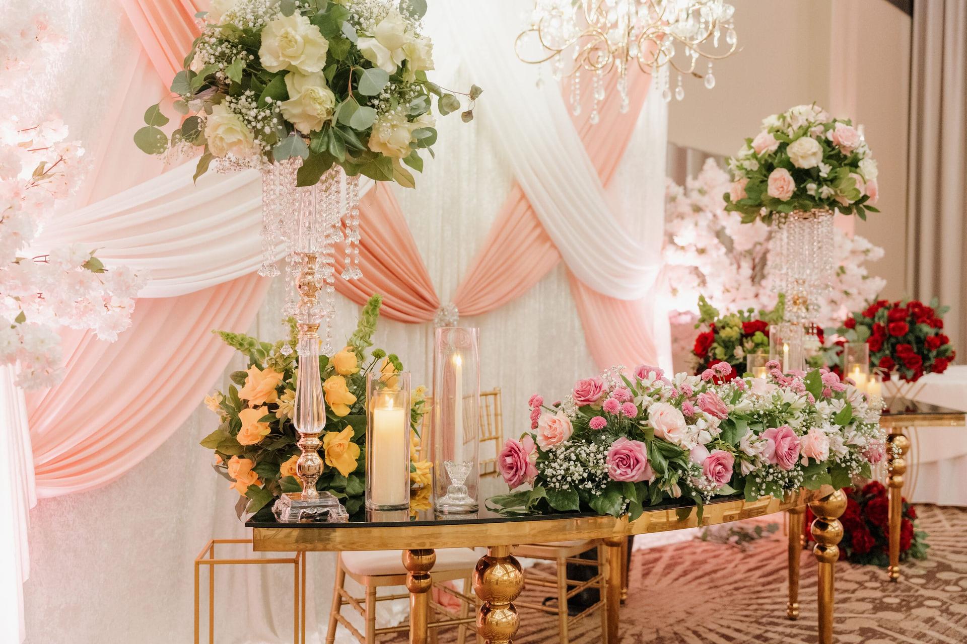 Sweetheart table with lush florals, pink and peach drapery, and gold accents.