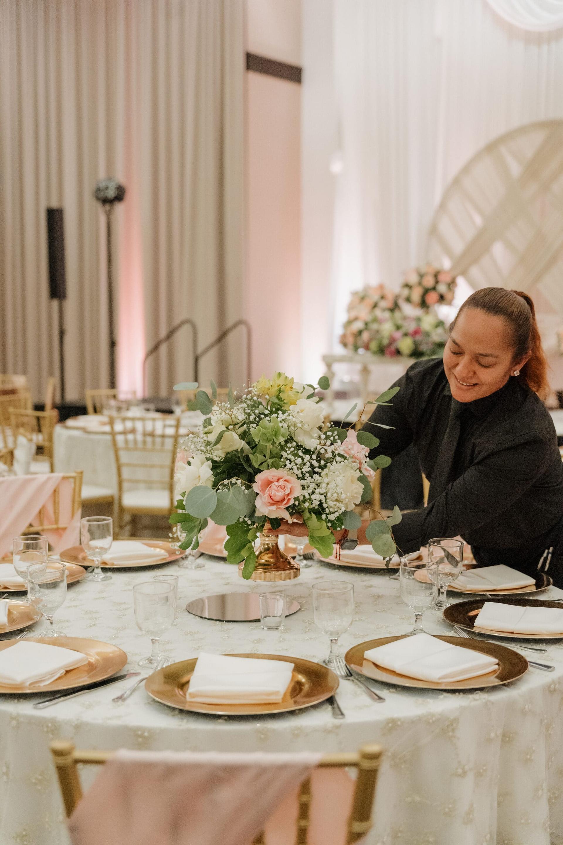 Staff arranging a floral centerpiece on a set table in the Grand Ballroom.