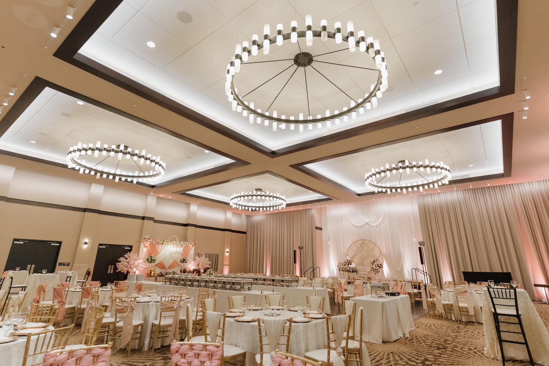 Grand Ballroom theater setup with coffered ceiling, ring chandeliers, and tables below.
