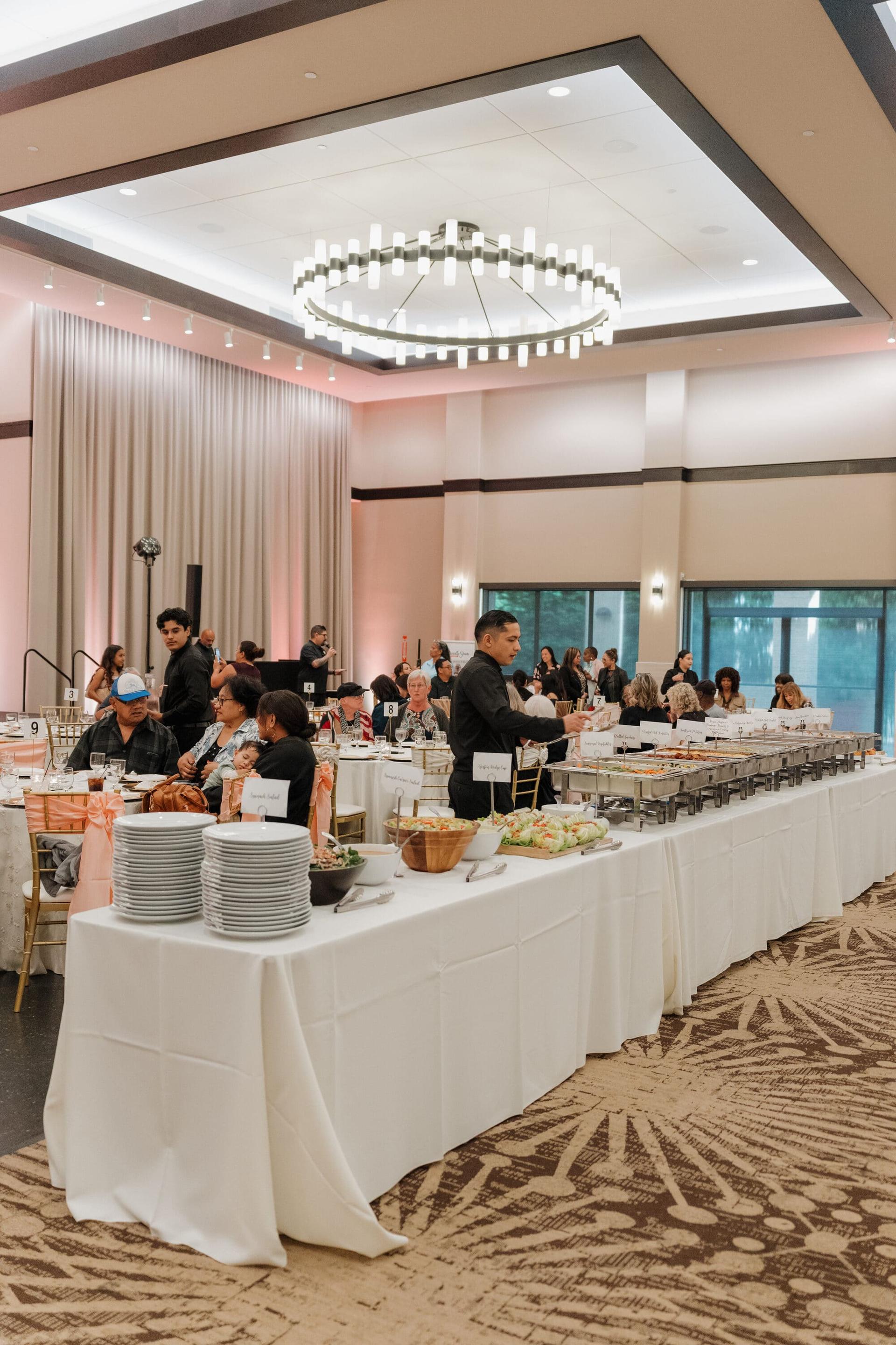 Guests and catering staff at a long buffet line in the Grand Ballroom.