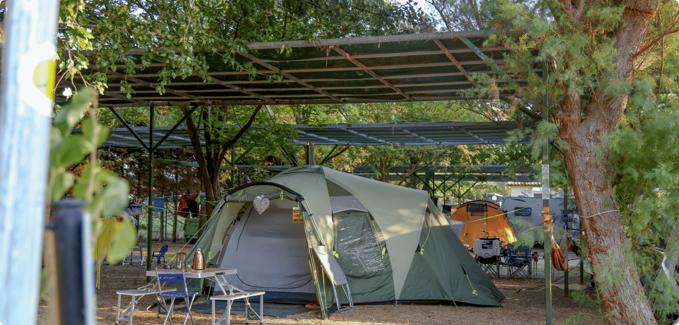 Picture of a large family tent, set at a large place under natural and artificial shadow.