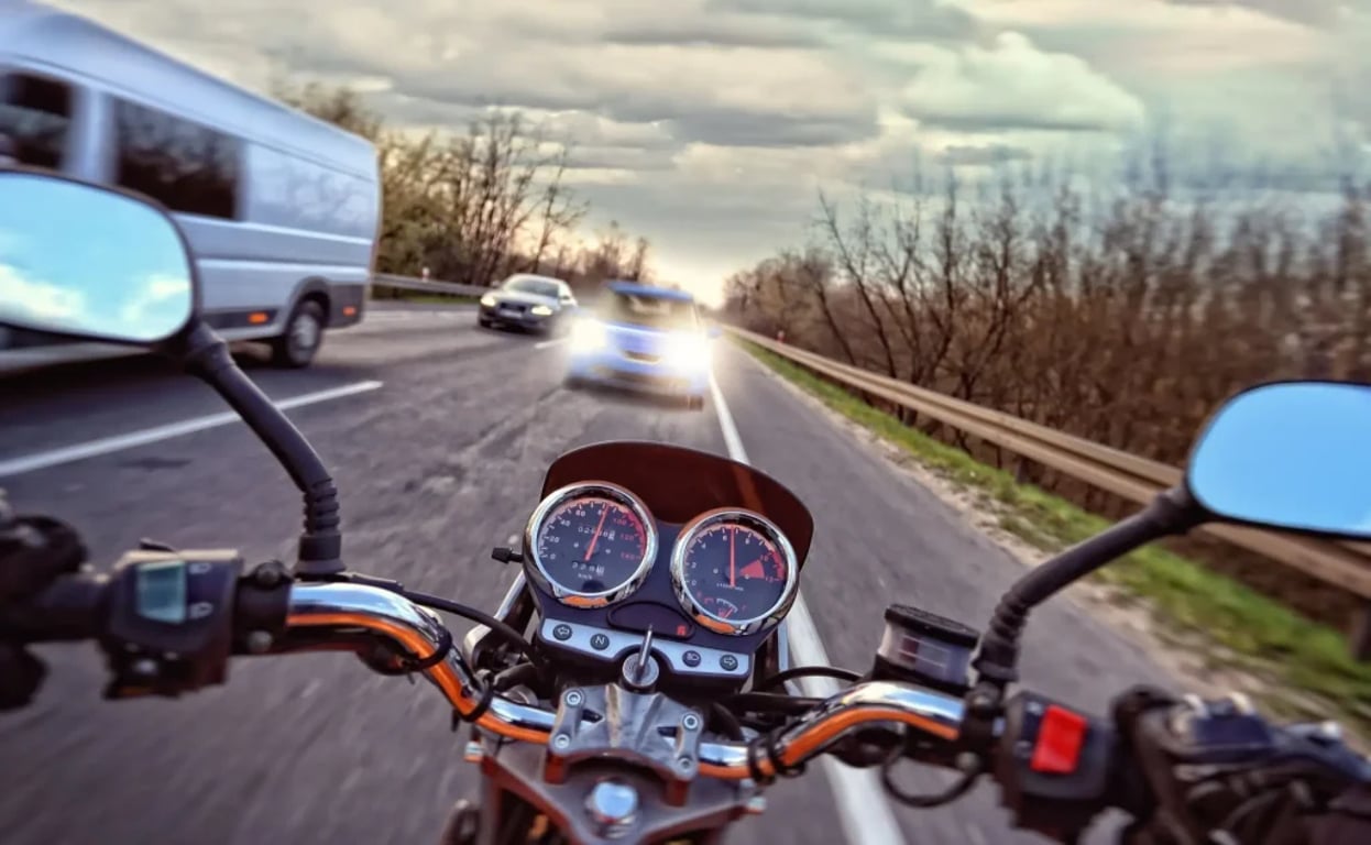 pohled motorkáře na těžkou dopravní situaci, proti němu jede řidič, který nebezpečně předjíždí v protisměru