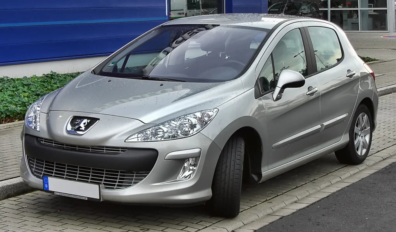 Stříbrný Peugeot 308 zaparkovaný před budovou