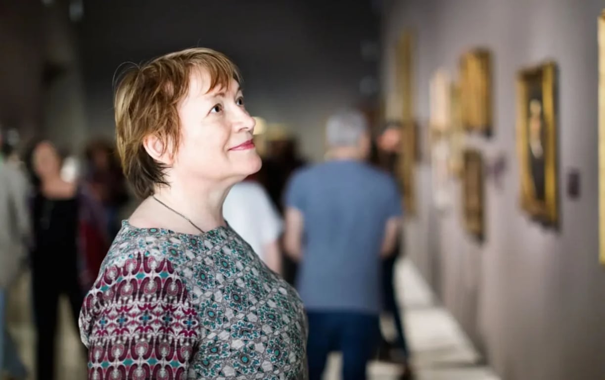Seniorka s úsměvem sleduje obrazy v galerii