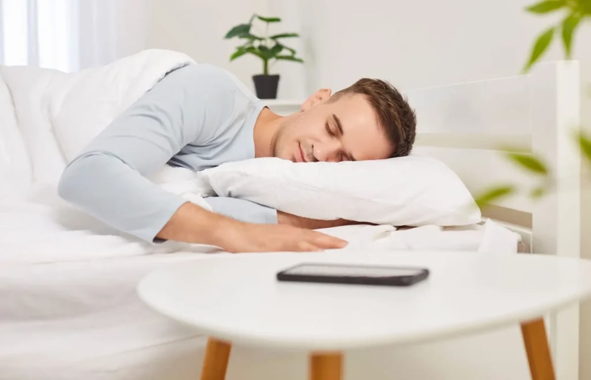 záběr na spícího muže, před ním mobil na stolečku