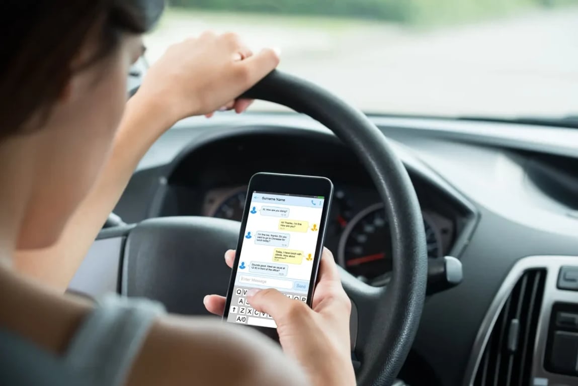 žena během řízení automobilu chatuje s kamarádkou na telefonu
