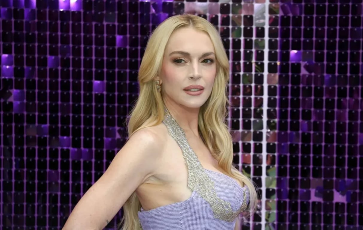 Blond žena v lesklých šatech pózuje před fialovým pozadím