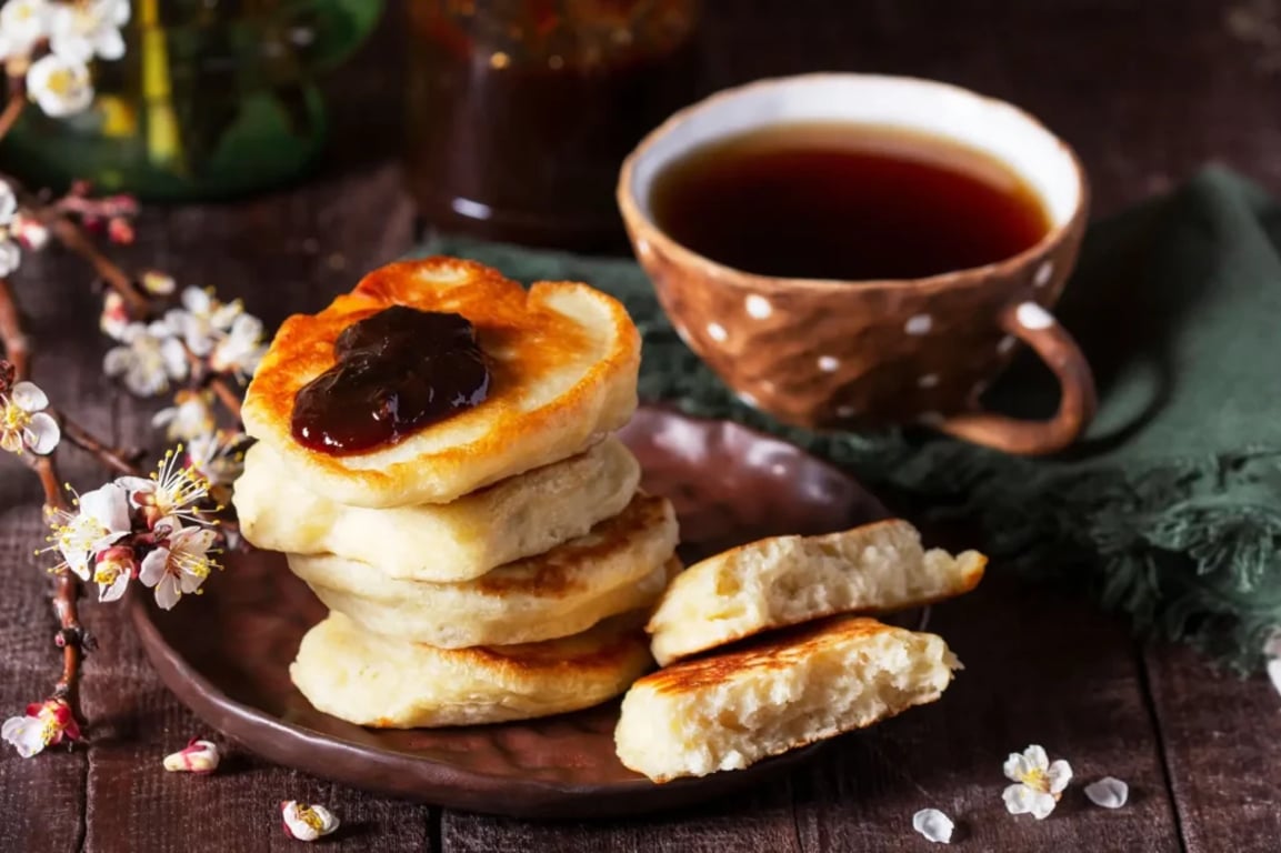 Nadýchané sladké alesniki s povidly a šálkem čaje na dřevěném stole