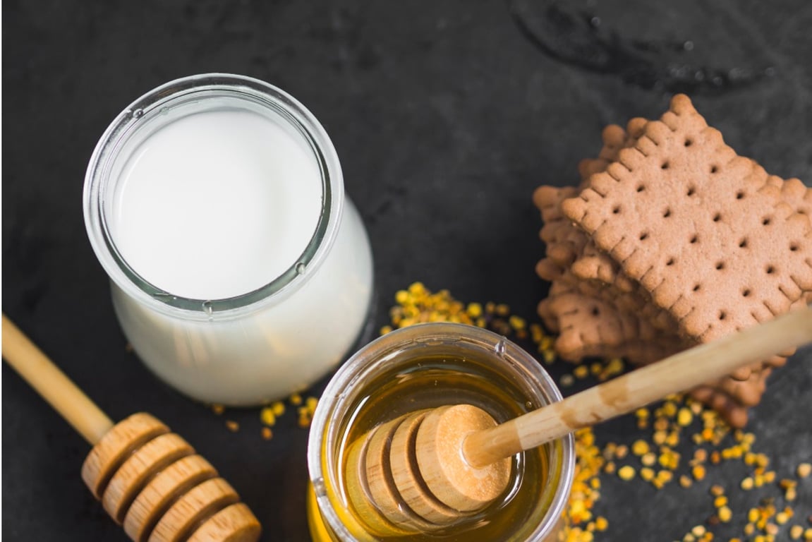 Pohled shora na sklenici mléka a medu se sušenkami