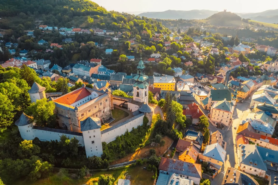 Letecký pohled na město Banská Štiavnica. Na levé straně jde vidět Starý zámek, poté ostatní domy města a zeleň okolí.
