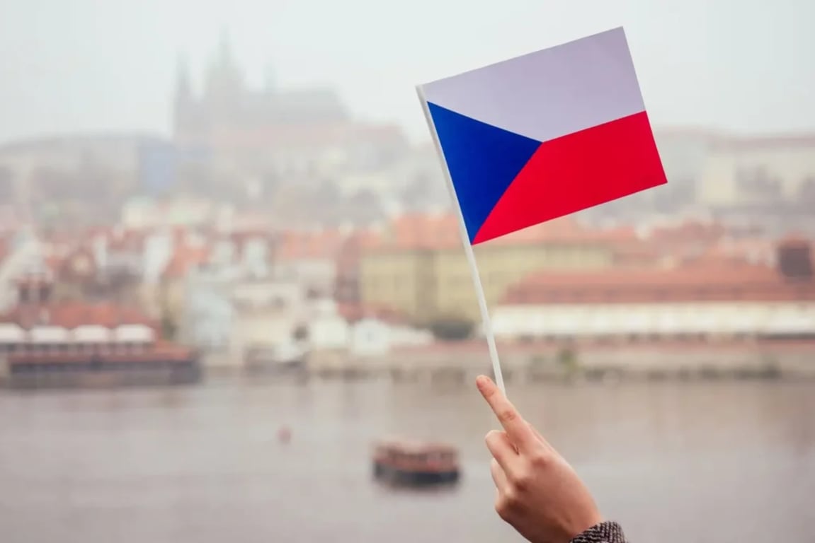 Ruka držící českou vlajku nad Prahou