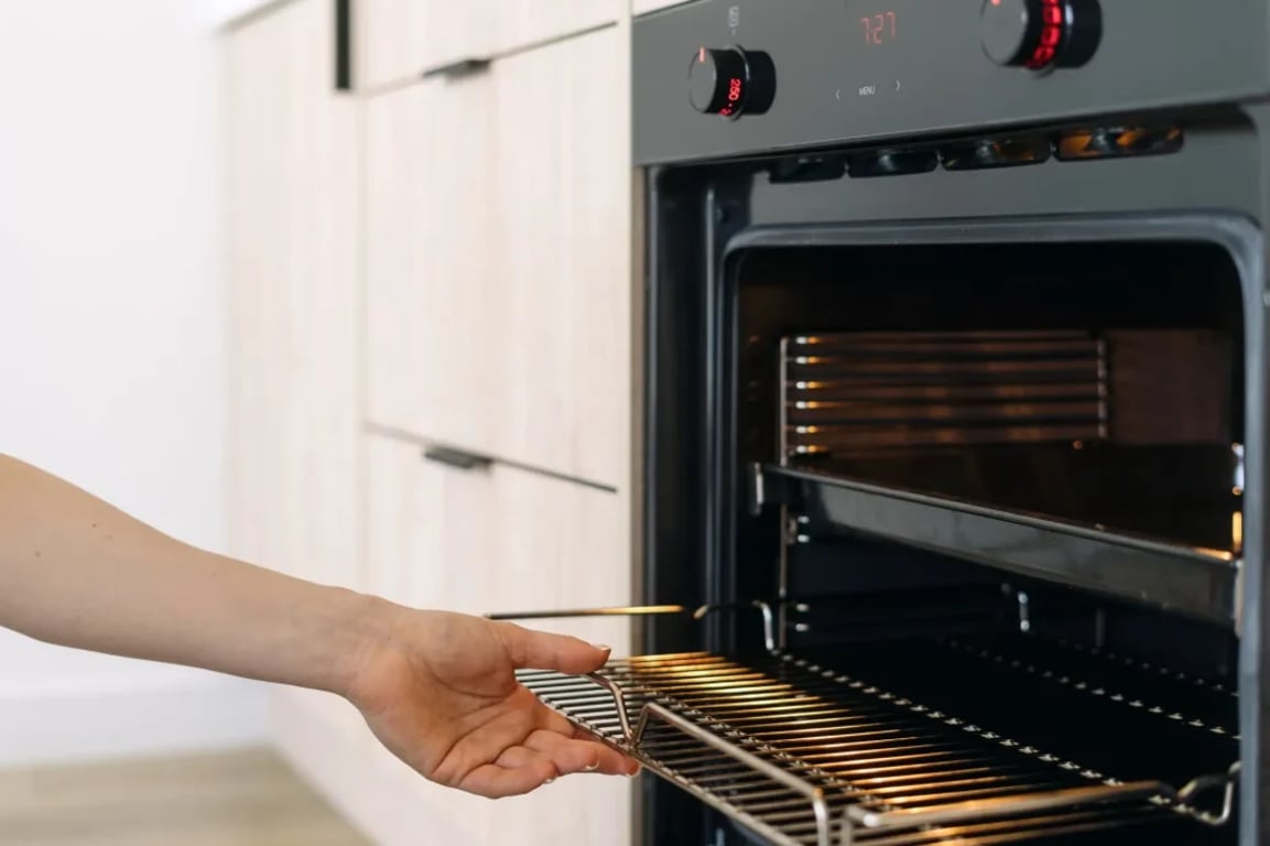 žena vytahuje rošt z trouby