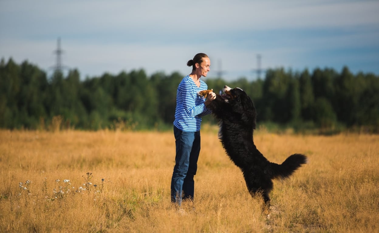 Muž chytá psovi tlapky při skákání