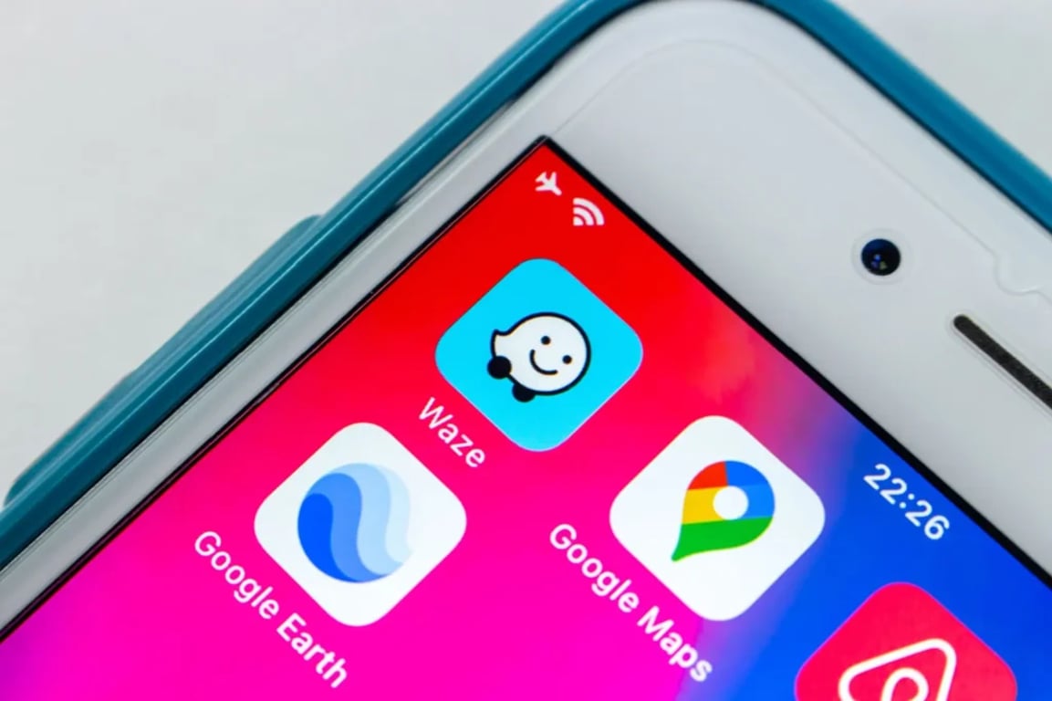 Detail displeje chytrého telefonu, na kterém jsou zobrazeny ikony několika navigačních aplikací. Mezi nimi je výrazně vidět Waze spolu s Google Earth a Google Maps.