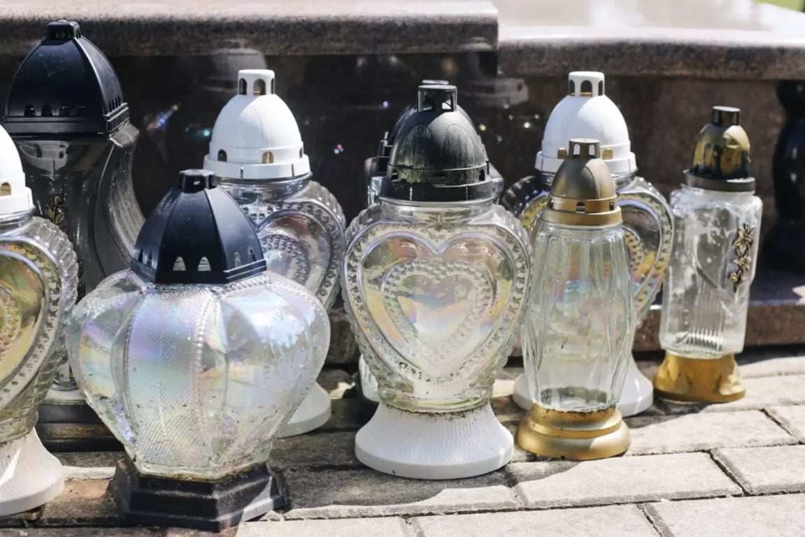 Prázdné skleněné svíčky postavené vedle hrobu