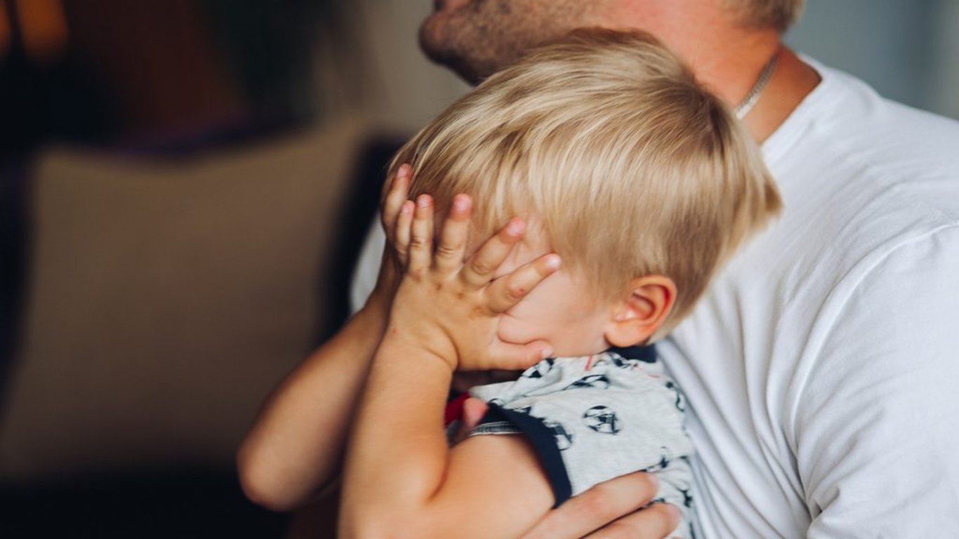 Plačící malý chlapec v náročí otce