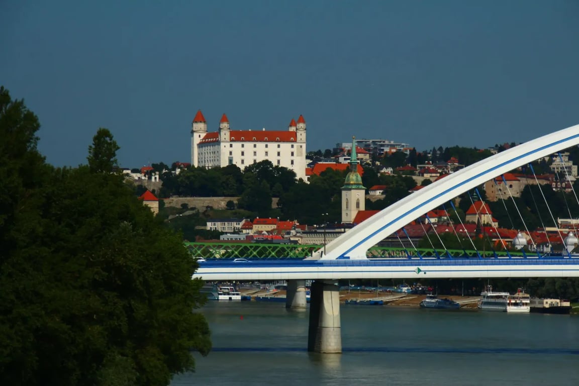 Letecký záběr na Bratislavu. Vidět jde řeka, přes kterou vede most a trochu v dálce Bratislavský hrad.