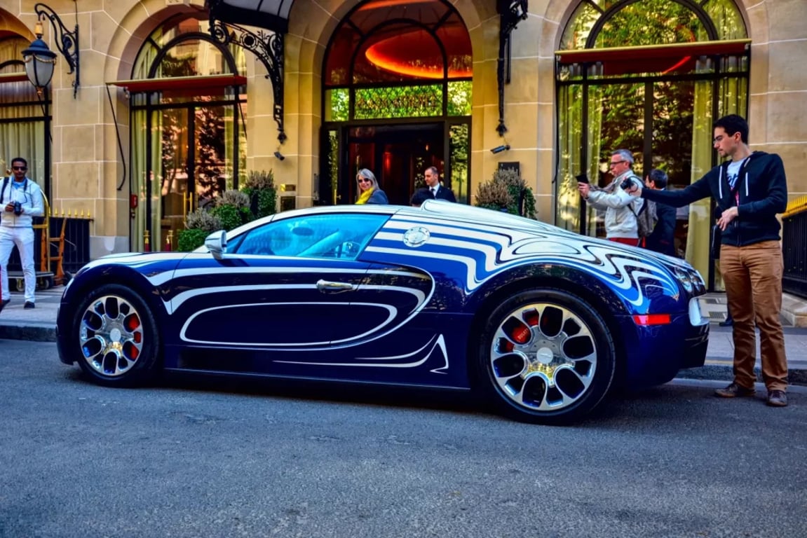 Bugatti Veyron ve velmi nápadném dvoubarevném lakování, zaparkované před luxusním hotelem. 