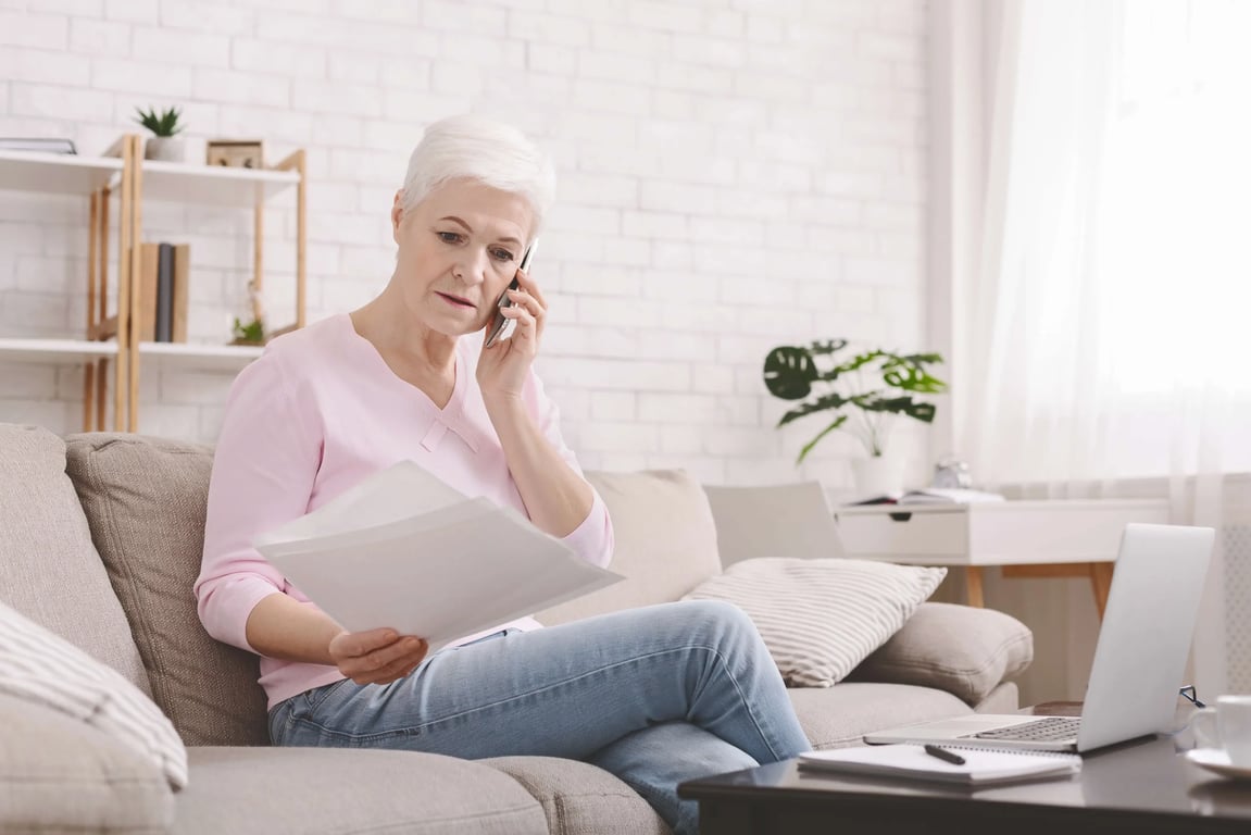 Seniorka telefonuje a má v ruce dokumenty.