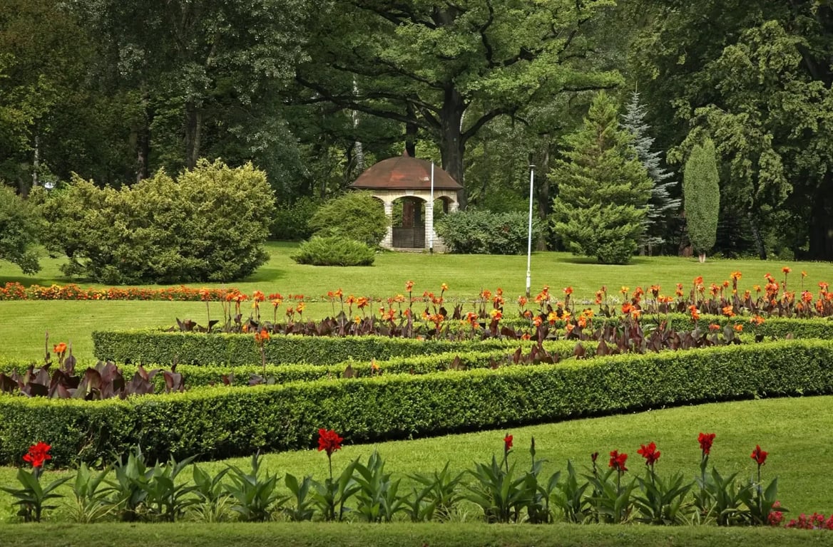 Krásný zelený park s květinami a malými živými ploty v obležení lesů v Kudowa-Zdroj. Polsko