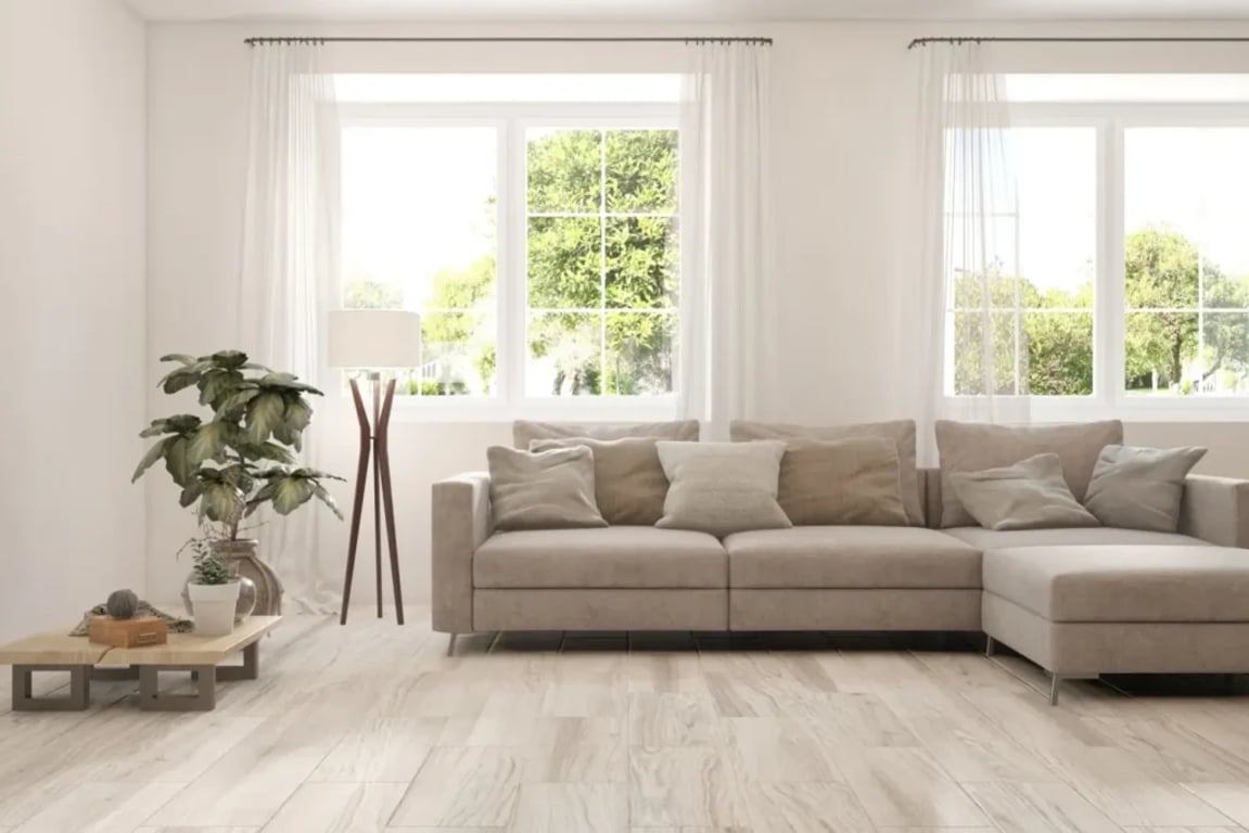 Obývací pokoj s béžovou sedačkou, zelenou rostlinou a bílými závěsy