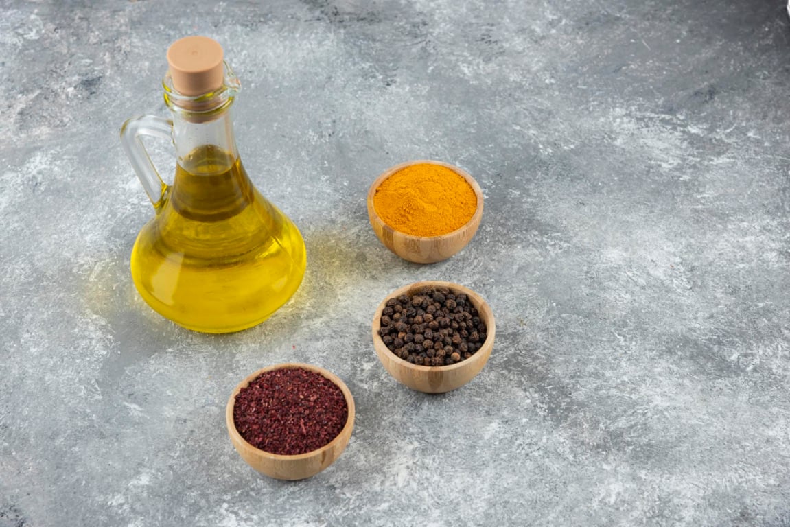Skleněná karafa s hořčičným olejem a tři misky s kořením