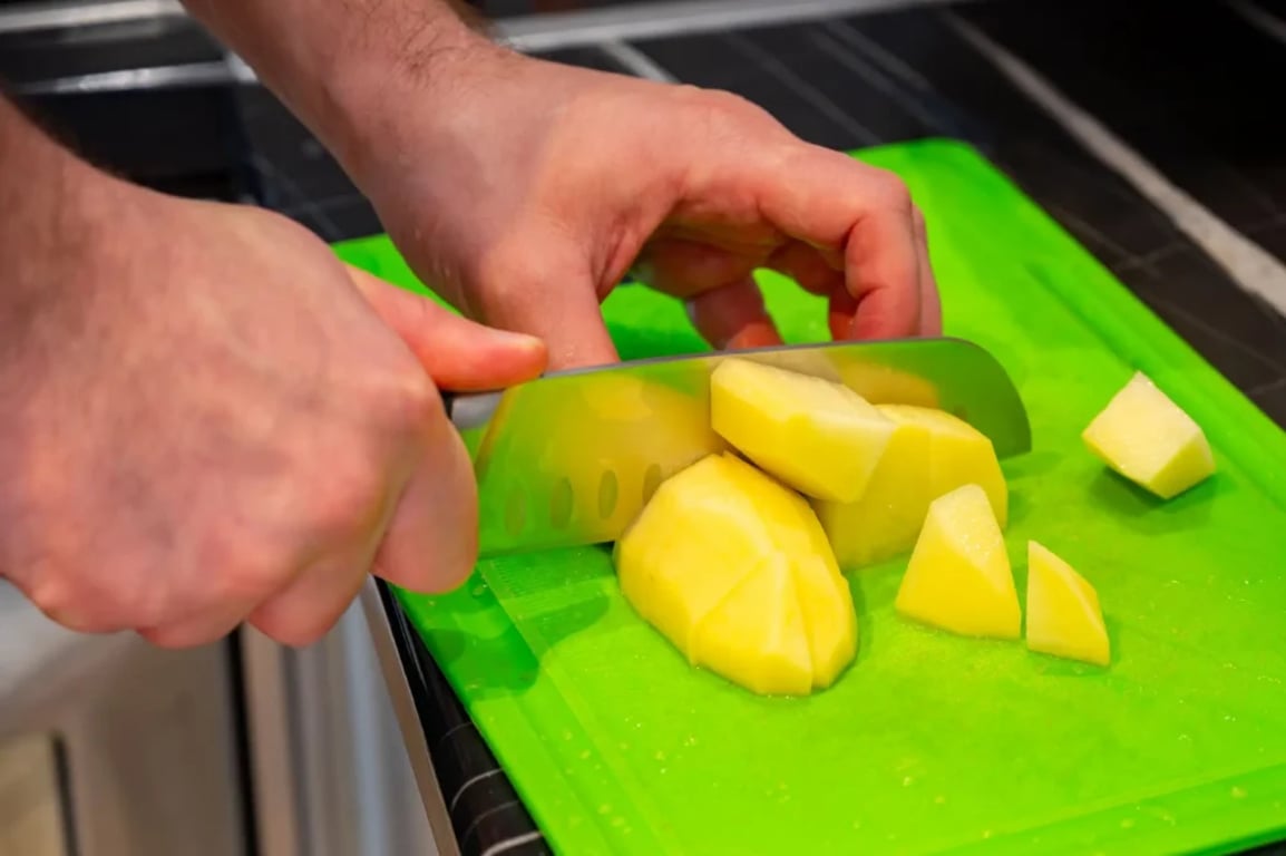 muž krájí brambory na větší kostky