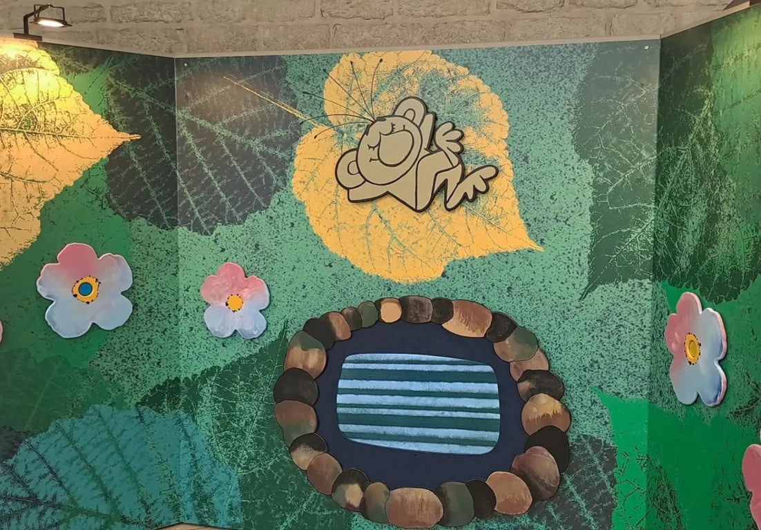 Ilustrace Rákosníčka ležícího na listu nad rybníkem Brčálník, obklopeného květinami