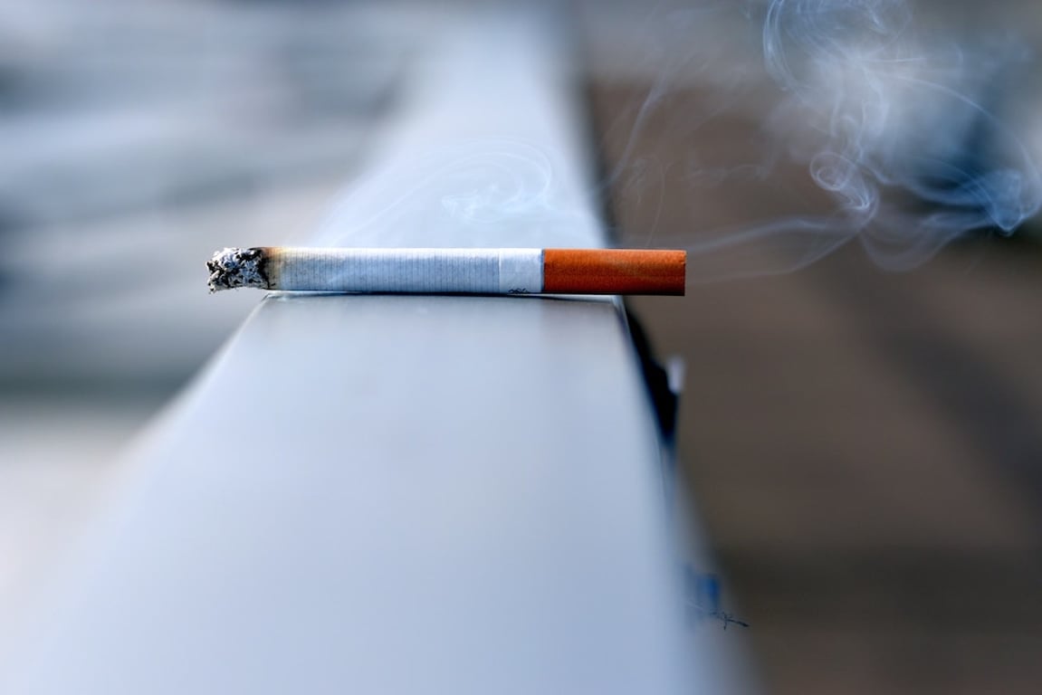Zapálená cigareta odložena na zábradlí