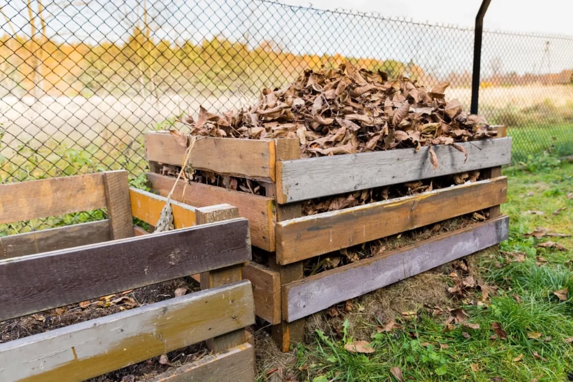 Kompost na zahradě, ve kterém je i spadané listí ze stromů