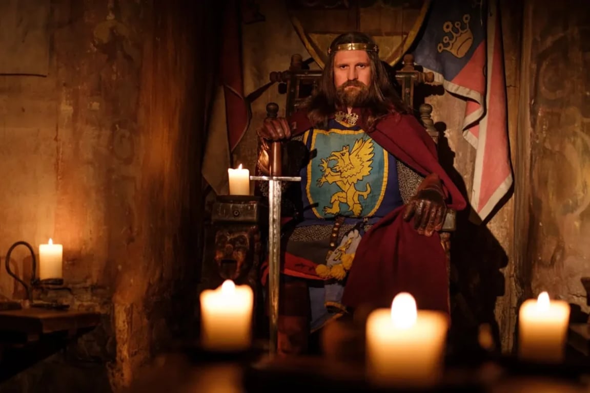 Král na trůnu se zbraní a hořícími svícemi