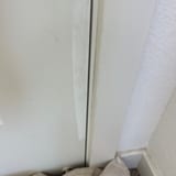 Close-up of a scuffed interior door edge and jamb next to a textured wall and baseboard.