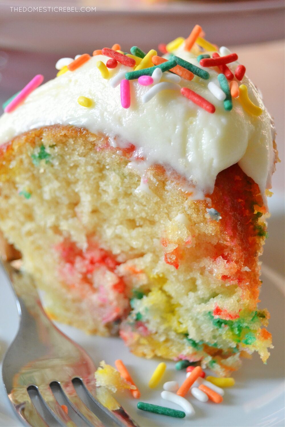 A Funfetti Bundt Cake with rainbow sprinkles and powdered sugar glaze.