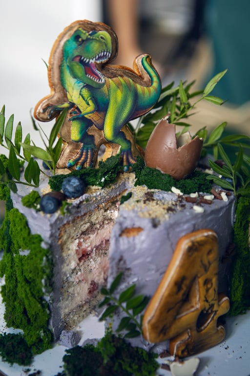 Dinosaur themed birthday cake with jungle decorations.