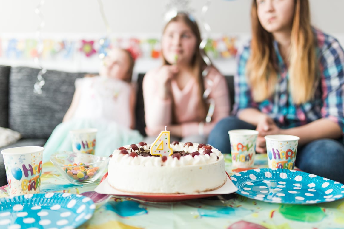 a birthday cake with the number 4 candle surrounded by party plates and other treats